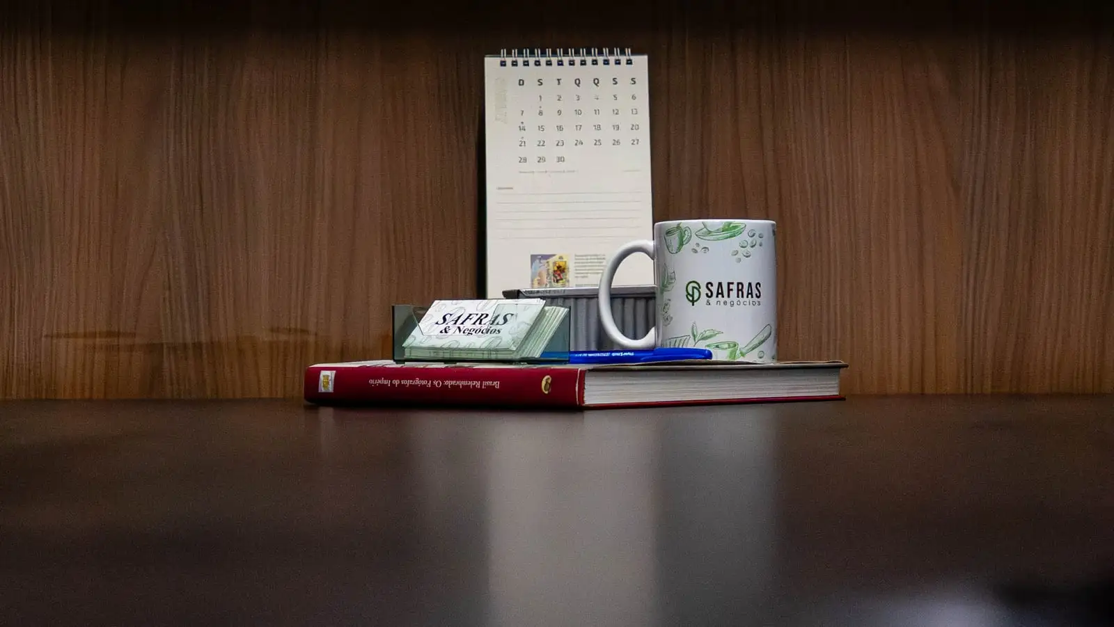 Mesa de escritório com agenda, caneca e cartões de visita da Safras & Negócios